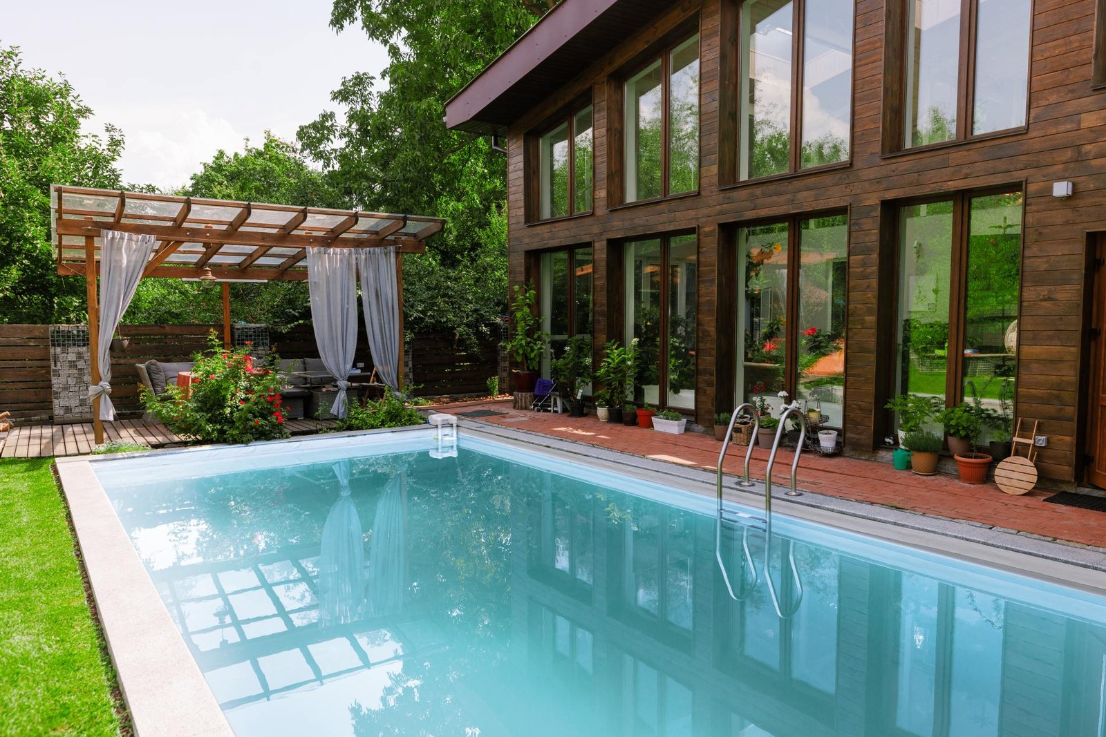 Piscine bordée d’une pergola devant une grande baie vitrée, pisciniste en Île-de-France